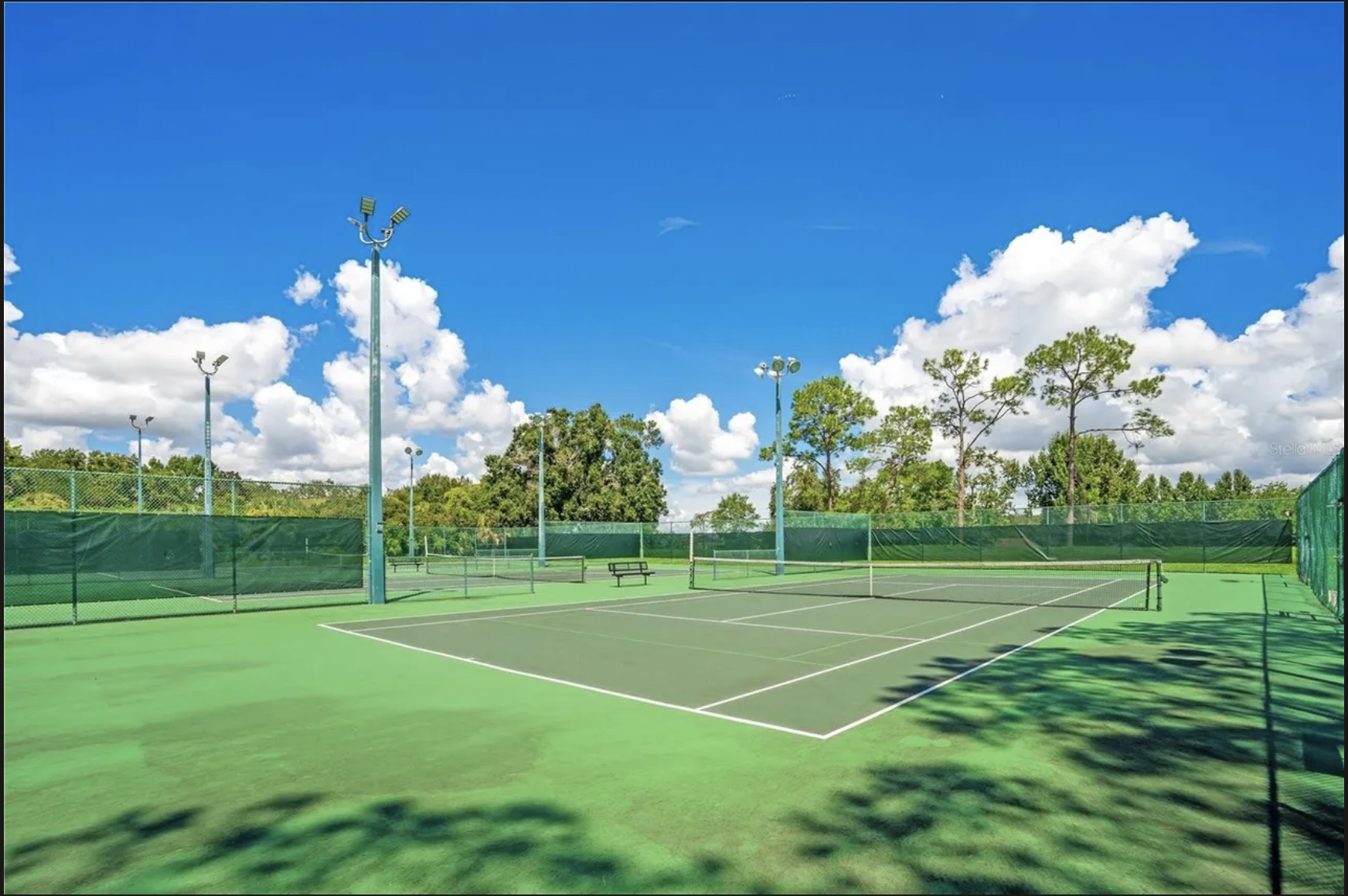Lighted tennis courts under a bright blue Florida sky