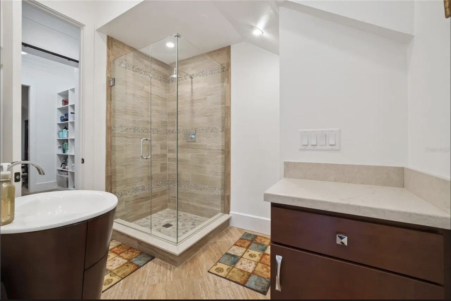 Bathroom with glass-enclosed tiled shower and dual vanities