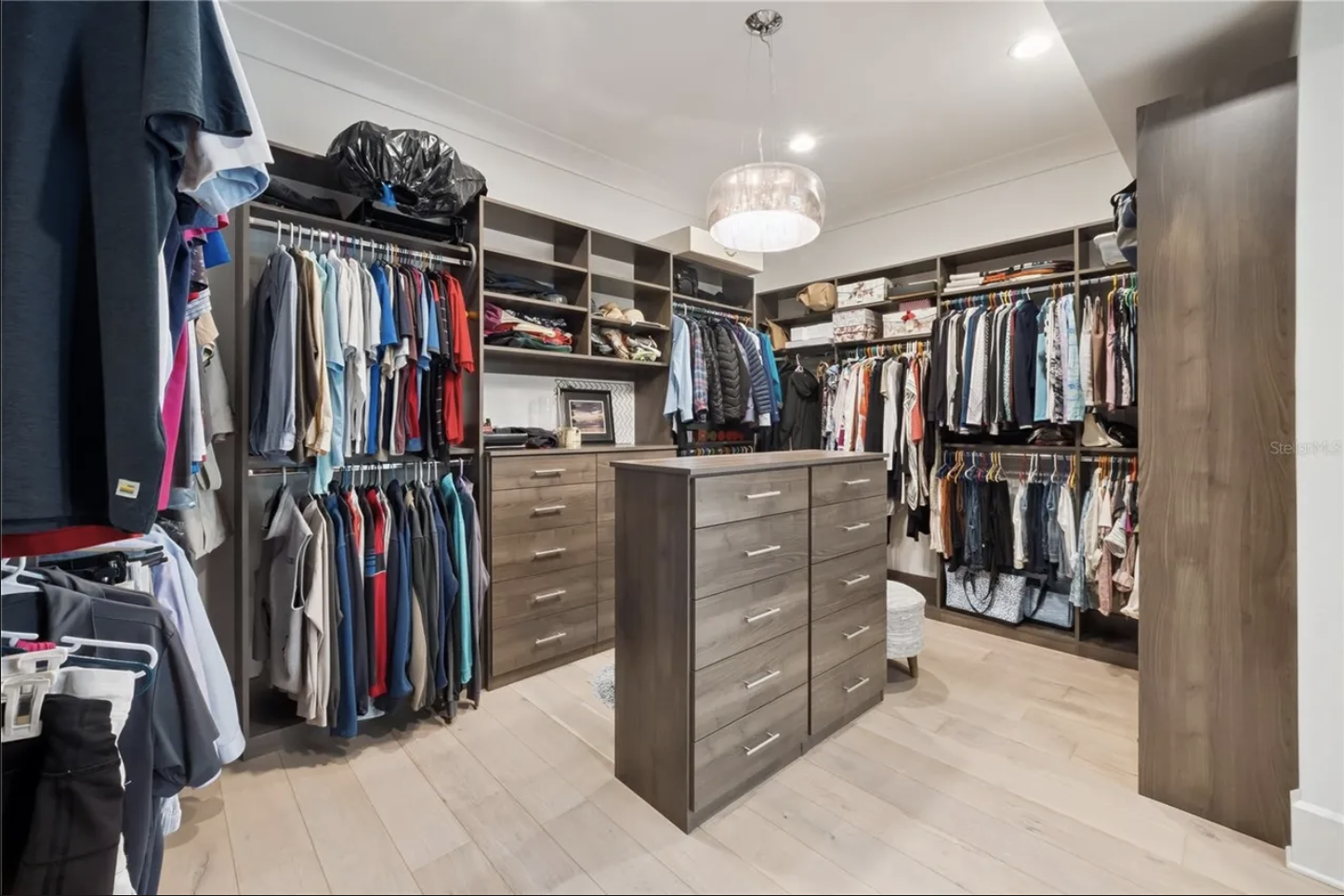 Custom walk-in closet with island dresser and built-in shelving
